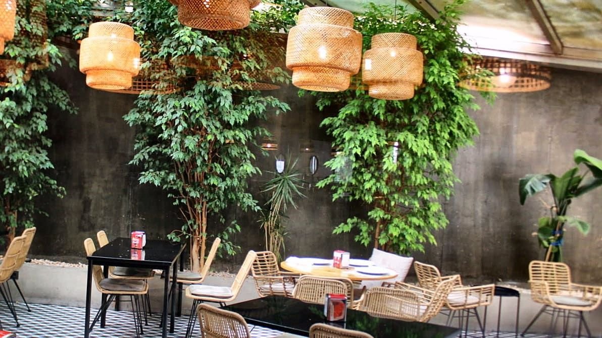 Pátio interior do Natura Caffé em Lousada com árvores e candeeiros de vime